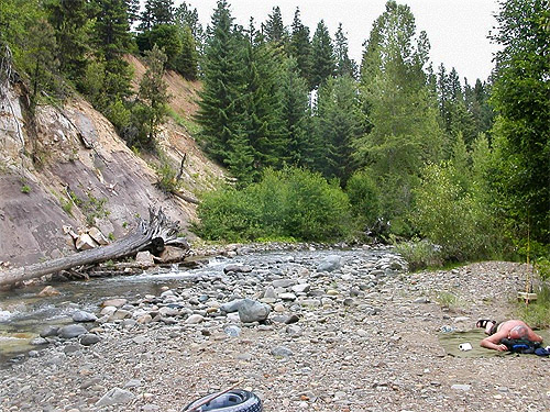 man sunbathing on cloudy day by North Fork Teanaway River, 29 Pines Campground, Kittitas County, Washington