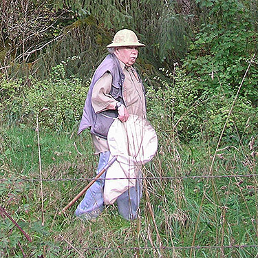 Rod Crawford walking along edge of large grassy field W of O'Toole Creek mouth, S shore Skagit River, Washington