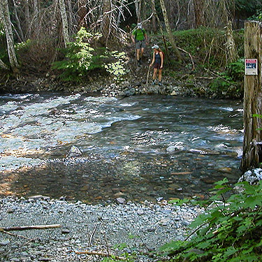 two hikers about to cross Kachess River north of Kachess Lake, Kittitas County, Washington